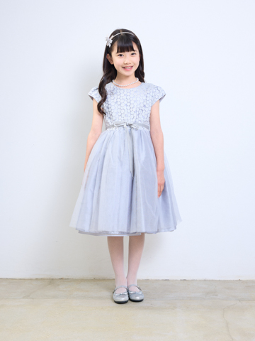 スカート部分のチュールがたっぷりあしらわれたボリュームのあるドレスです。フレンチスリーブが季節をとわないデザインで、上身頃部分にはラメ入り糸の刺繍であしらわれたドット柄が華やかな印象。ウエスト部分には、前にベルベット生地のリボン。後ろはチュール部分と同じ生地のリボンでとてもキュート。シルバーの色合いがとても上品なドレスです。